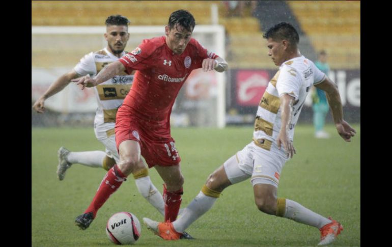 Rubens Sambueza disputa el balón con dos jugadores de Sinaloa. TWITTER / TolucaFC