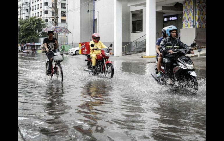 Motociclistas circulan por una calle inundada en Makati, donde el tifón 'Hato' causó considerables daños. EFE / R. Cristino