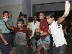 Rescatistas voluntarios de Dacca cargan a un niño víctima del incendio. Las autoridades dan como cifra oficial 109 muertos. AP  /