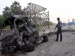 Un policía inspecciona un vehículo quemado en el lugar donde explotó un coche bomba en el barrio de Al-Amil, al sur de Bagdad. EFE  /