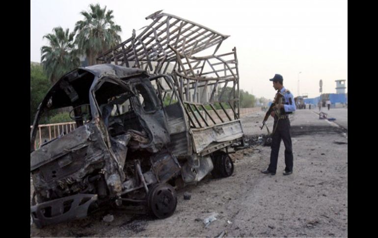 Un policía inspecciona un vehículo quemado en el lugar donde explotó un coche bomba en el barrio de Al-Amil, al sur de Bagdad. EFE  /