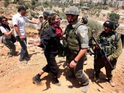 Militares israelíes confrontan a activistas que se inconforman por la barda fronteriza entre Israel y la ciudad cisjordana. AFP  /