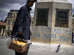 Un vendedor pasa frente a un monumento en Plaza Bolívar donde se lee el rechazo a las relaciones con Estados Unidos. AFP  /