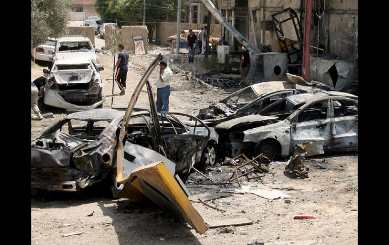 Iraquíes observan los daños causados por uno de los coches-bomba, en el Centro de Bagdad. EFE  /