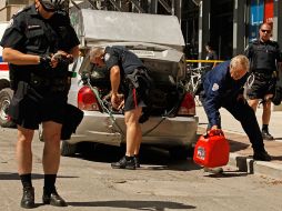 Policías transportan los contenedores con gasolina hallados en un auto. AFP  /