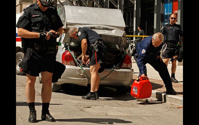 Policías transportan los contenedores con gasolina hallados en un auto. AFP  /