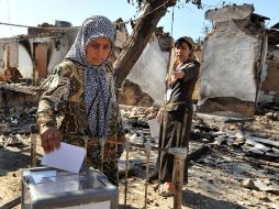 Mujeres uzbekas votan a unos metros de las ruinas de su casa, ante el miedo de sufrir ataques, durante las elecciones en Osh. AFP  /