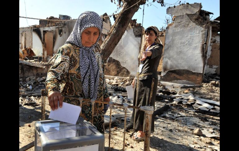 Mujeres uzbekas votan a unos metros de las ruinas de su casa, ante el miedo de sufrir ataques, durante las elecciones en Osh. AFP  /