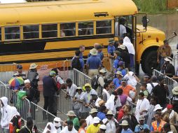 Trabajadores esperan subir a unos autobuses para reanudar sus actividades de limpieza en Grand Isle. EFE  /