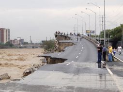 Varias personas observan la destrucción que causó la corriente del Río Santa Catarina en un paso elevado en Monterrey. REUTERS  /