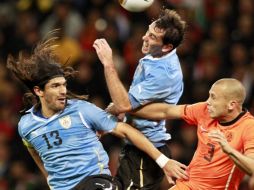 El jugador holandés, John Heitinga (der.) disputa un balón con los uruguayos Sebastián Abreu (izq.) y Diego Godín. EFE  /