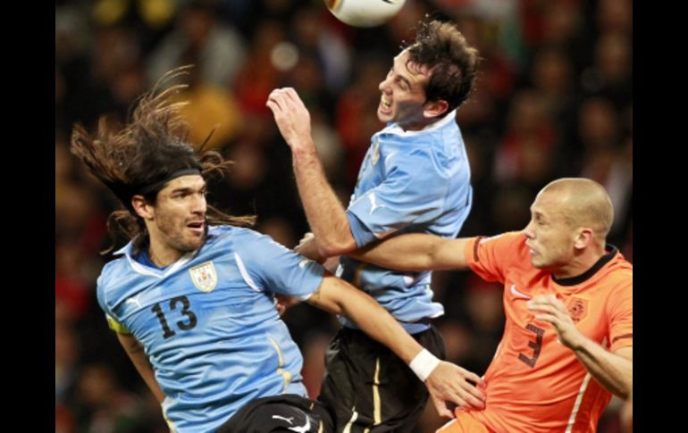 El jugador holandés, John Heitinga (der.) disputa un balón con los uruguayos Sebastián Abreu (izq.) y Diego Godín. EFE  /