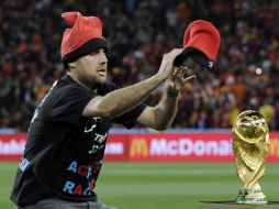 El aficionado en su intento por ponerle un gorro a la Copa del Mundo. AP  /