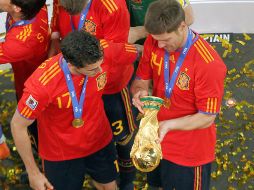 Los españoles Álvaro Arbeloa y Xabi Alonso observan minuciosamente la Copa de la FIFA que ganaron ayer. GETTY IMAGES SPORT  /