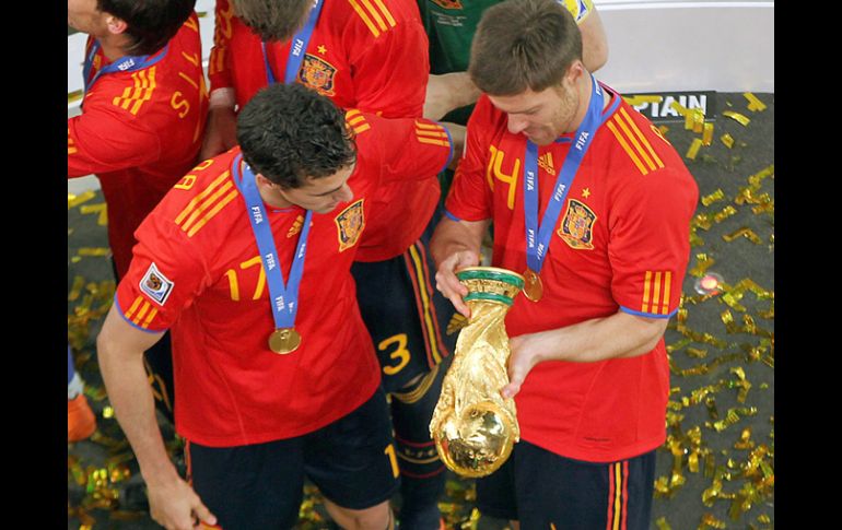 Los españoles Álvaro Arbeloa y Xabi Alonso observan minuciosamente la Copa de la FIFA que ganaron ayer. GETTY IMAGES SPORT  /