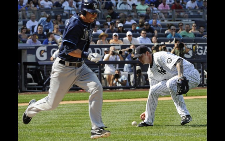 A.J. Burnett recoje la bola mientras Ben Zobrist corre a primera durante la segunda entrada. AP  /