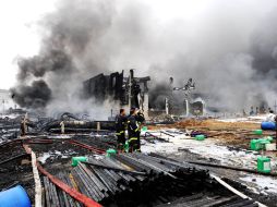 Bomberos observan los destrozos causados por el incendio. AFP  /