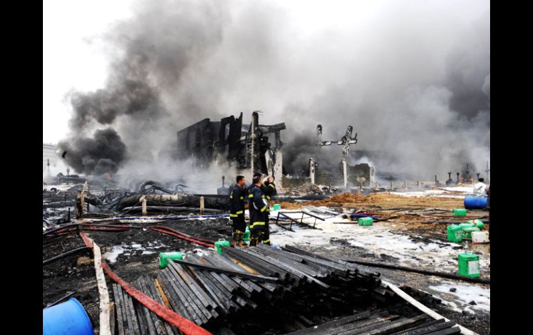 Bomberos observan los destrozos causados por el incendio. AFP  /