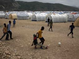 Ñinos juegan futbol en un campamento para damnificados en Haití, 1.7 millones de haitianos aún no tienen vivienda.  AP  /