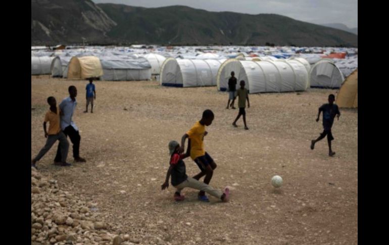 Ñinos juegan futbol en un campamento para damnificados en Haití, 1.7 millones de haitianos aún no tienen vivienda.  AP  /