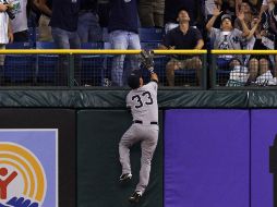 Nick Swisher de los Yankees escala el muro para intentar impedir el jonrón de Matt Joyce. AP  /