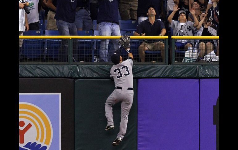 Nick Swisher de los Yankees escala el muro para intentar impedir el jonrón de Matt Joyce. AP  /