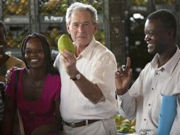 El ex presidente George W. Bush muestra un mango, acompañado del dueño de la empresa Ralph Perry, y de unas trabajadoras. EFE  /