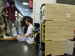 Los pasajeros varados cuelgan carteles de protesta en los pasillos del aeropuerto de Madrid. EFE  /