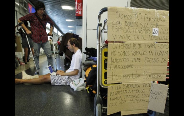 Los pasajeros varados cuelgan carteles de protesta en los pasillos del aeropuerto de Madrid. EFE  /