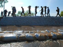 Miembros del Ejército Mexicano y civiles hacen una barricada con sacos de arena en las márgenes del Río Grijalva en Villahermosa. EFE  /