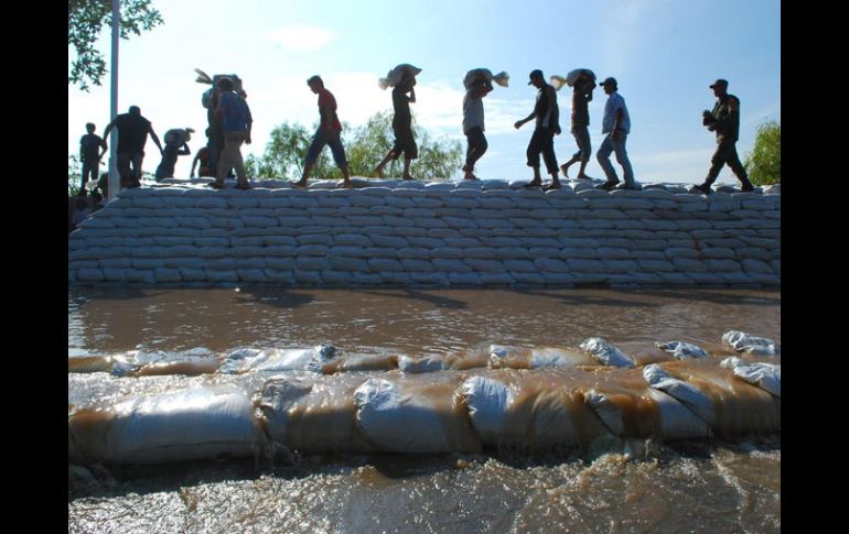 Miembros del Ejército Mexicano y civiles hacen una barricada con sacos de arena en las márgenes del Río Grijalva en Villahermosa. EFE  /