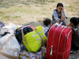 Gitanos rumanos que han llegado de Francia descansan junto a su equipaje en el aeropuerto Internacional de Bucarest. EFE  /