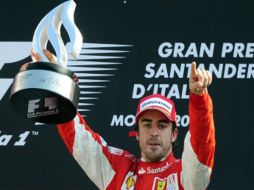 Fernando Alonso subió a lo más alto del podio y festeja su victoria con el trofeo en mano. AFP  /