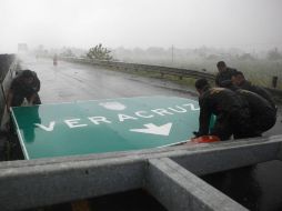 Policías quitan hoy un señalamiento de tránsito que se cayó en la carretera cerca de Cardel, Veracruz, debido a los fuertes vientos. AP  /