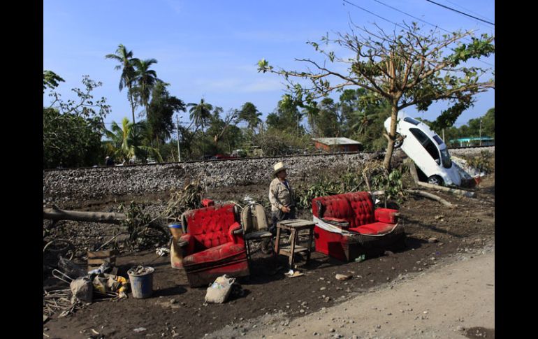 Un habitante de Samoral, en Veracruz, camina entre muebles llenos de lodo y un carro dañado por las inundaciones. REUTERS  /