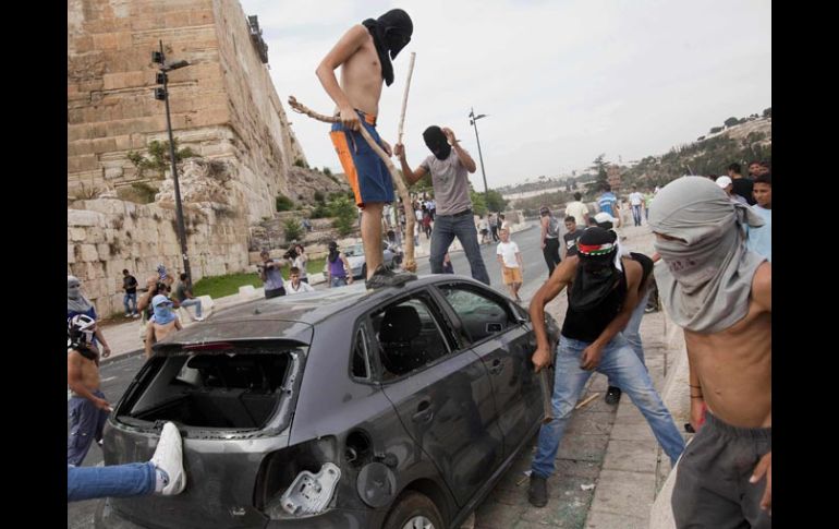 Palestinos arruinan un automóvil durante el enfrentamiento contra policías israelíes, en Jerusalén. AP  /