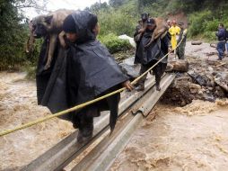 Rescatistas cargan a sus perros al pasar por un puente improvisado. Sigue la búsqueda de cuerpos sepultados por un alud. EFE  /