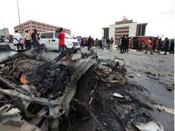 La gente de pie alrededor de los restos después de que un coche bomba explotó en Abuja, Nigeria. AP  /