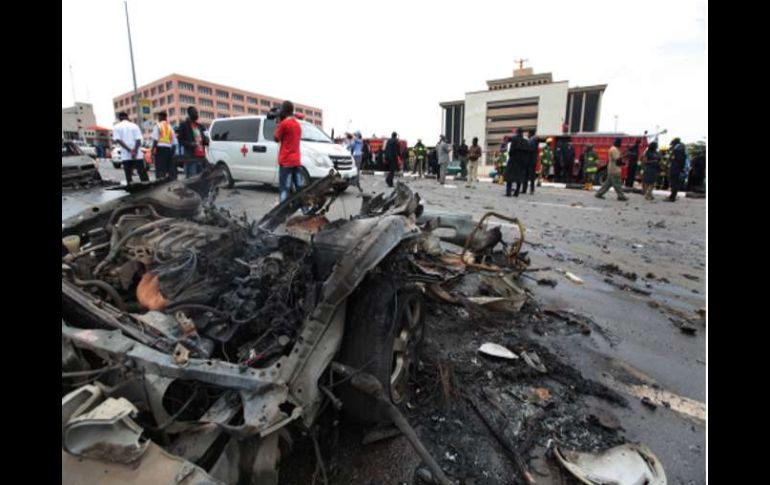 La gente de pie alrededor de los restos después de que un coche bomba explotó en Abuja, Nigeria. AP  /