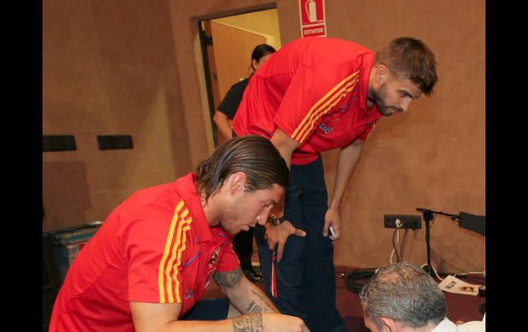 Los defensas de la selección española de fútbol Sergio Ramos izq, y Gerard Piqué, firman autógrafos antes de una rueda de prensa. EFE  /