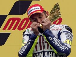 El piloto italiano Valentino Rossi festeja su victoria besando su trofeo. AP  /