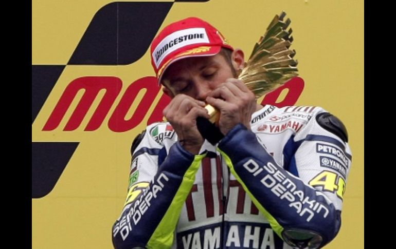 El piloto italiano Valentino Rossi festeja su victoria besando su trofeo. AP  /