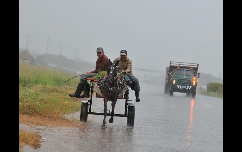 Dos hombres viajan en una carreta bajo una intensa lluvia provocada por la proximidad del huracán ‘‘Paula’’. EFE  /