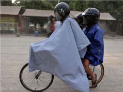 Los residentes en bicicleta por un camino cubierto de una gruesa capa de ceniza en Yogyakarta. AFP  /