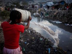 Una haitiana arroja agua sucia a un desagüe.REUTERS  /