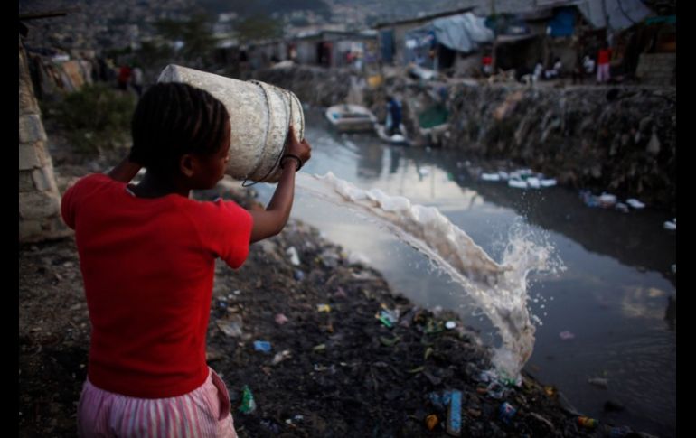 Una haitiana arroja agua sucia a un desagüe.REUTERS  /