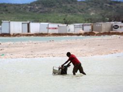 Un niño empuja una silla de ruedas por el inundado Malpase, en Haití. EFE  /