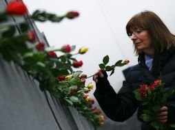 Una mujer decora las ruinas del Muro de Berlín en el vigésimo primer aniversario de su caída. AP  /