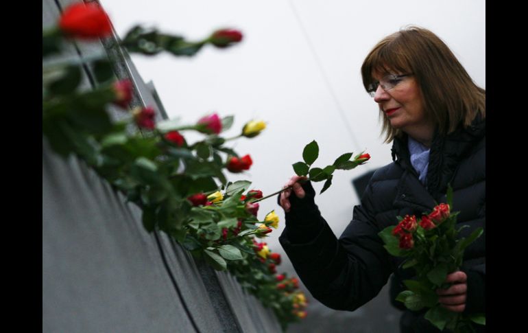 Una mujer decora las ruinas del Muro de Berlín en el vigésimo primer aniversario de su caída. AP  /