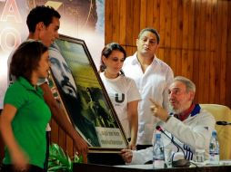 Fidel Castro (d), habla con los estudiantes mientras recibe un cuadro en el que es representado de joven. AP  /